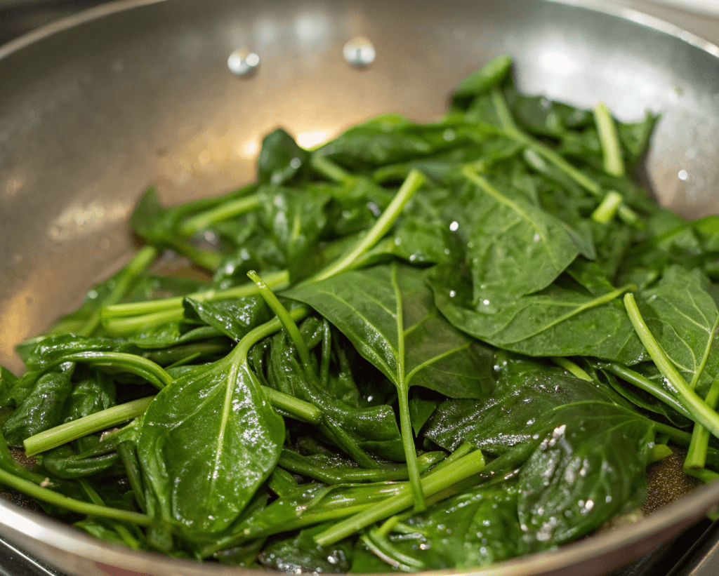 Sautéed sweet potato leaves in a pan.